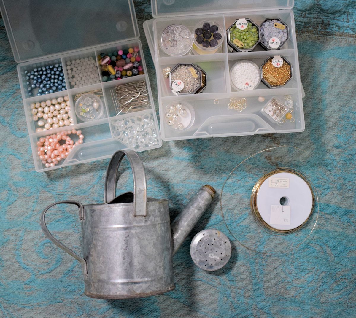 Kastelukannun tuunaus tarvikkeet: sinkkikastelukannu, helmiä ja ohutta rautalankaa.